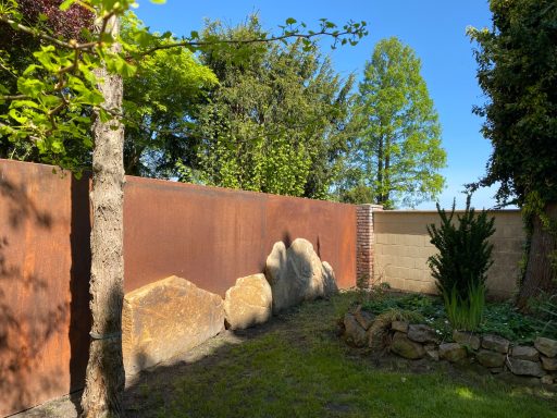 Gartensichtschutz Elemente Ein Garten mit einem rustikalen Zaun und grüner Vegetation im Sonnenschein.